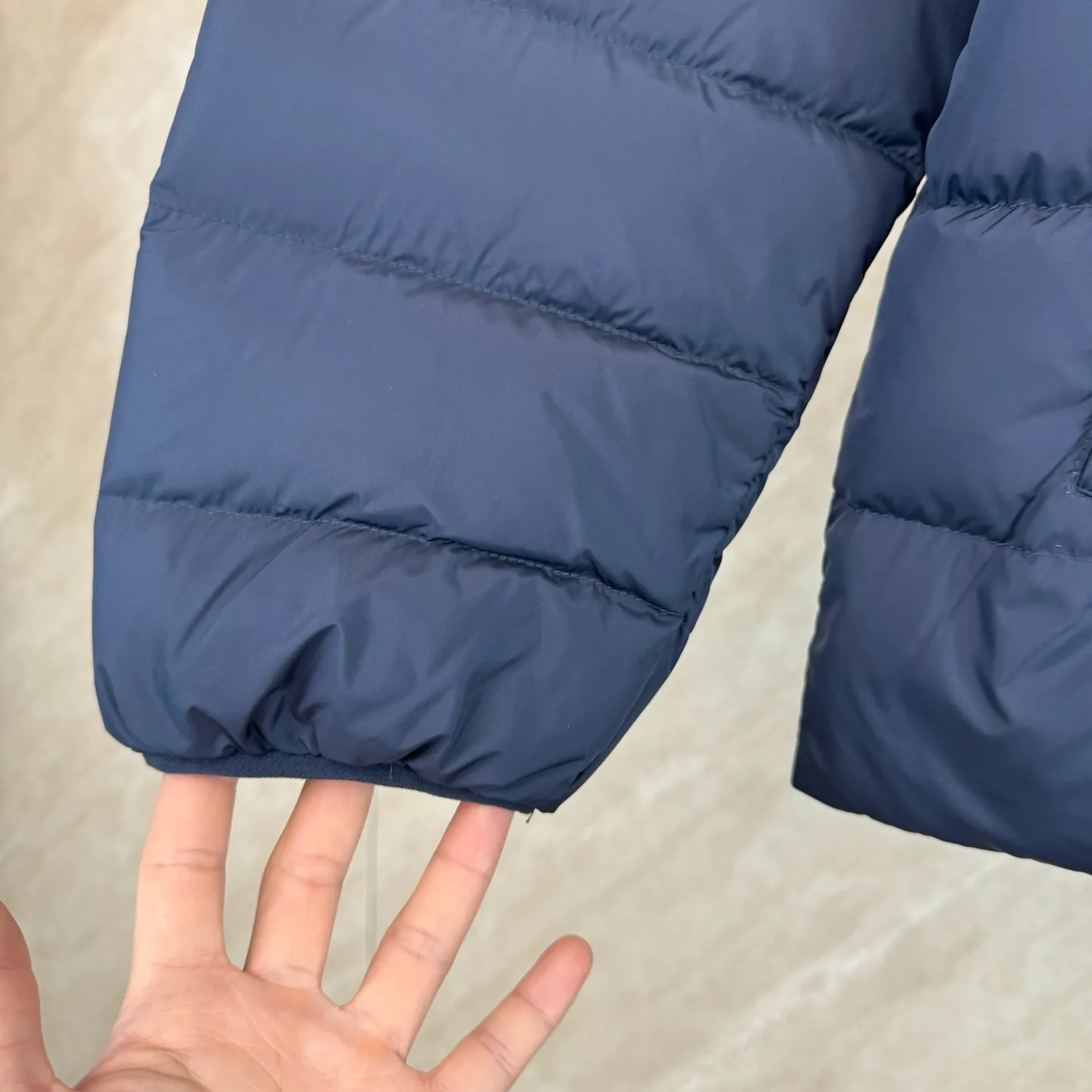 P930 lightweight down jacket size s m l xl Nylon fabric has good windproof and waterproof properties, which can effectively block the intrusion of wind and rain from the outside and keep the inside dry, suitable for wearing in humid or rainy environments.  The red label on the chest is made with an imported MECLO embroidery machine. The original pattern is scanned first, and then high-quality silk thread is used to make a pattern. The density effect is adjusted by continuous pattern making.  Exquisite details: the zipper design is simple and elegant, easy to operate; the closing design of the cuffs and hem effectively prevents the intrusion of cold wind, improving the warmth and comfort of wearing.  High-quality filling: 90 white duck down is selected, with a weight of 260g, ensuring excellent thermal insulation performance. After strict screening and processing, the velvet is not easy to drill, ensuring durability. The hangtags, wash marks, air holes, and four-button buttons are all customized from the original one-to-one mold.
